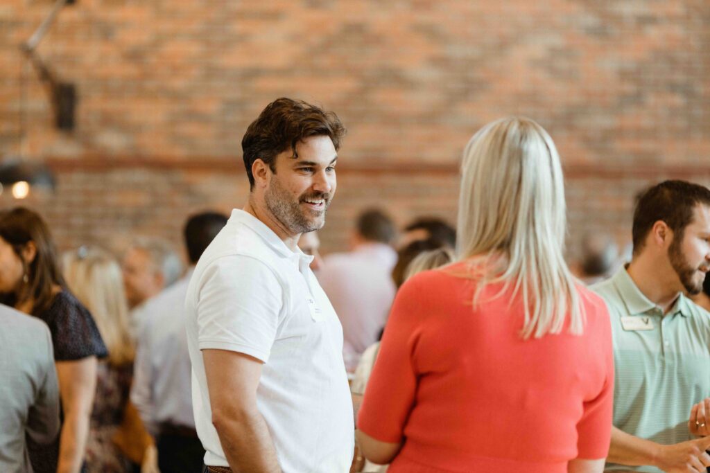 A man with a friendly smile engages in conversation at a social event.