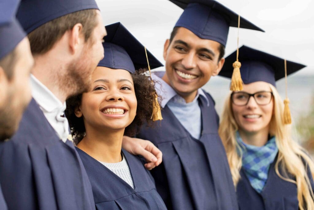 A group of joyful graduates wearing caps and gowns, celebrating their academic achievements with smiles.