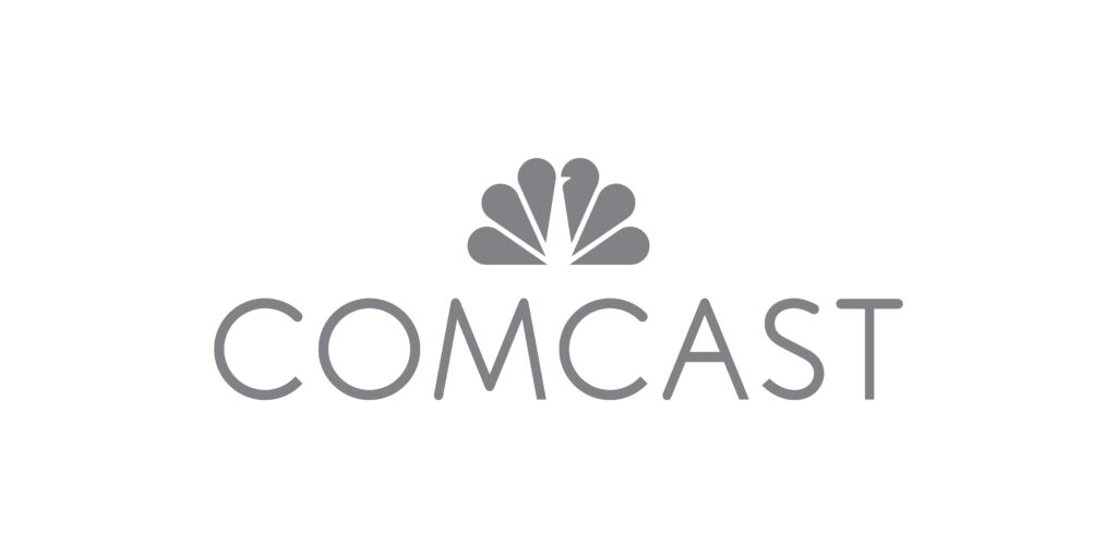 The image shows the logo of comcast, which is a telecommunications company. the logo features the company's name in a sans-serif font with a stylized flower or peacock emblem above, symbolizing the company's range of services and broadcasting capabilities.