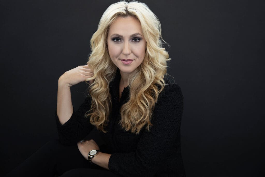 Elegant woman posing with confidence against a black backdrop, exuding grace and poise.