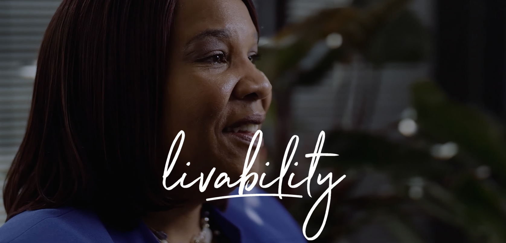 A woman mid-speech with an air of confidence, against an indoor background softly blurred, with the word "livability" stylishly inscribed at the forefront.
